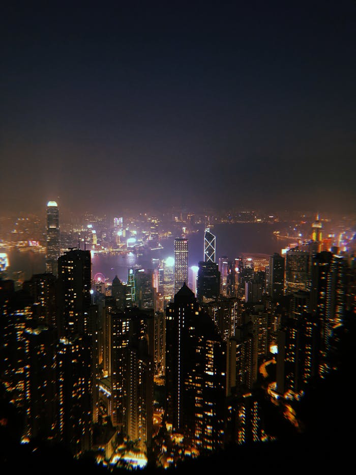 Modern city with glowing lights and skyscrapers under cloudless dark sky at night